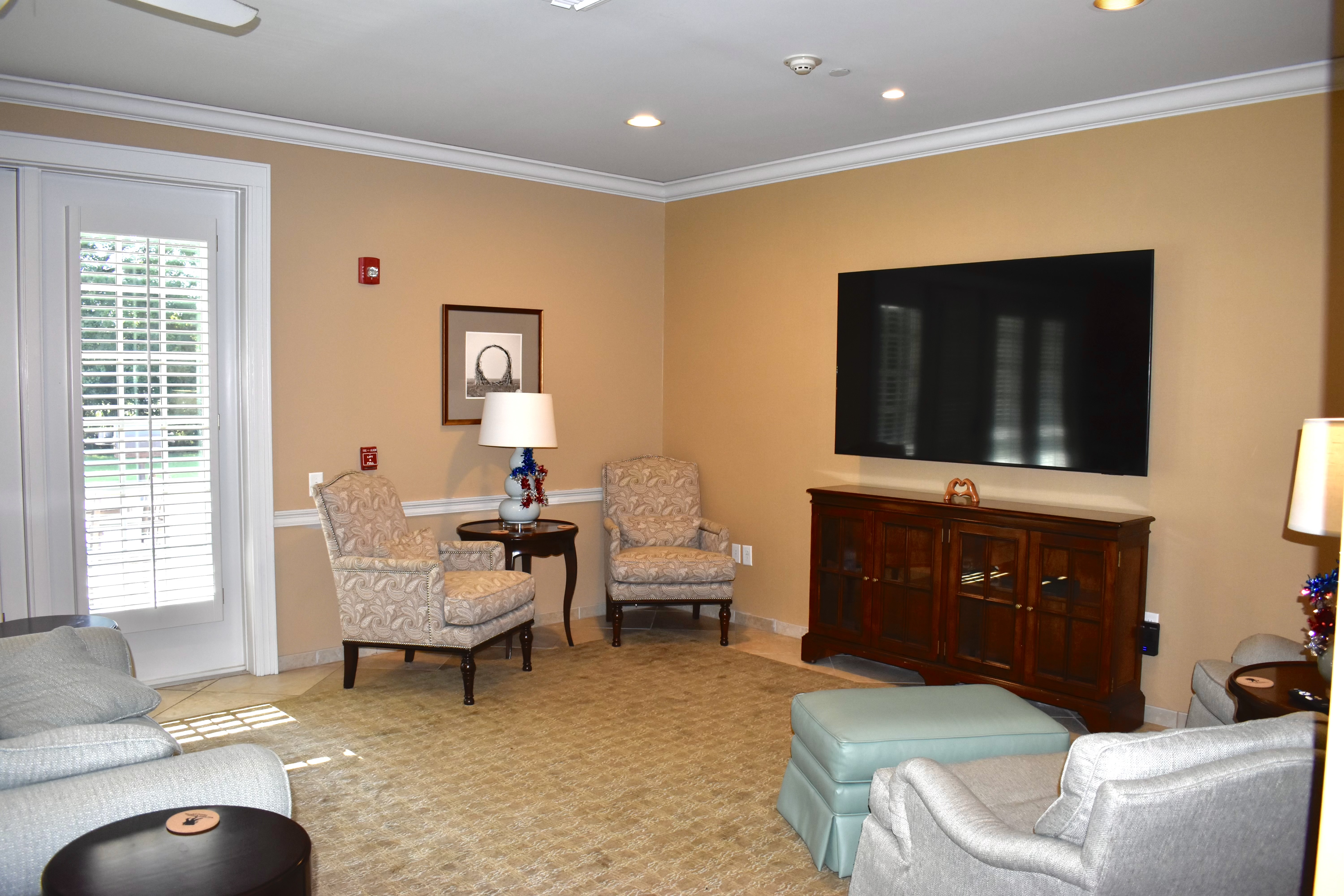 Sunlit Fisher House common room with sofas, armchairs, and warm daylight inviting families to gather.